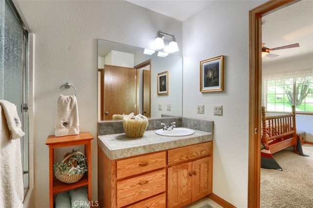 full bath featuring vanity, a textured wall, baseboards, and ceiling fan