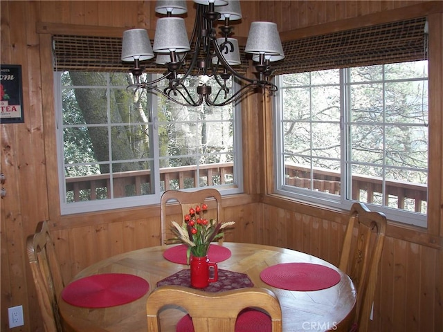 dining area with an inviting chandelier and wood walls