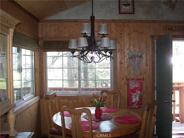 dining room featuring wooden walls, lofted ceiling, and a healthy amount of sunlight