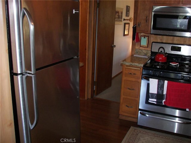 kitchen with brown cabinets, stainless steel appliances, and dark wood-style flooring