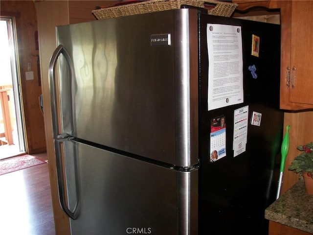 interior details featuring brown cabinetry, freestanding refrigerator, and wood finished floors