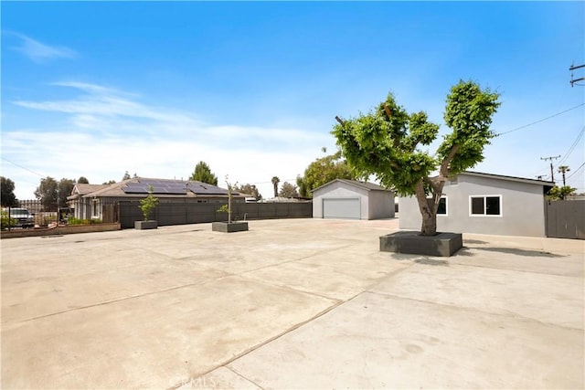 view of front of property with an outbuilding, a detached garage, fence, a patio, and stucco siding