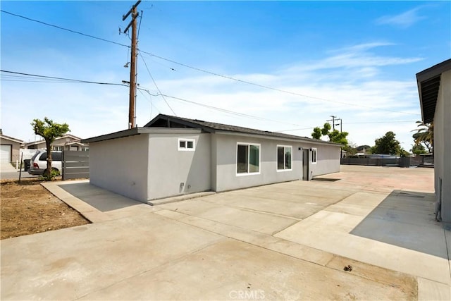 rear view of property with a patio area, stucco siding, and fence