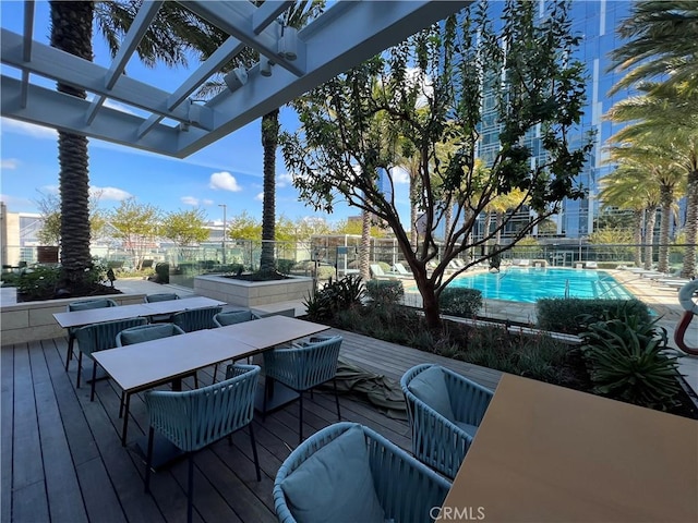 wooden deck with fence, a pergola, outdoor dining area, and an outdoor pool