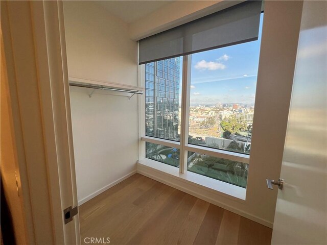 interior space with a view of city, baseboards, and wood finished floors