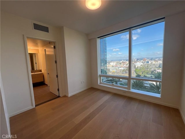 interior space with a city view, baseboards, visible vents, and wood finished floors