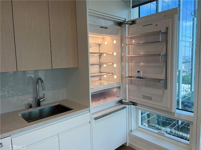 kitchen featuring a sink, decorative backsplash, modern cabinets, and light countertops