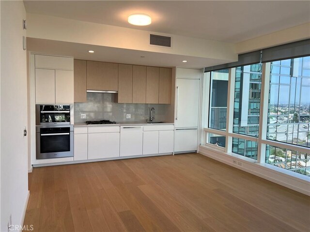kitchen with visible vents, light wood-type flooring, tasteful backsplash, dishwasher, and black gas stovetop