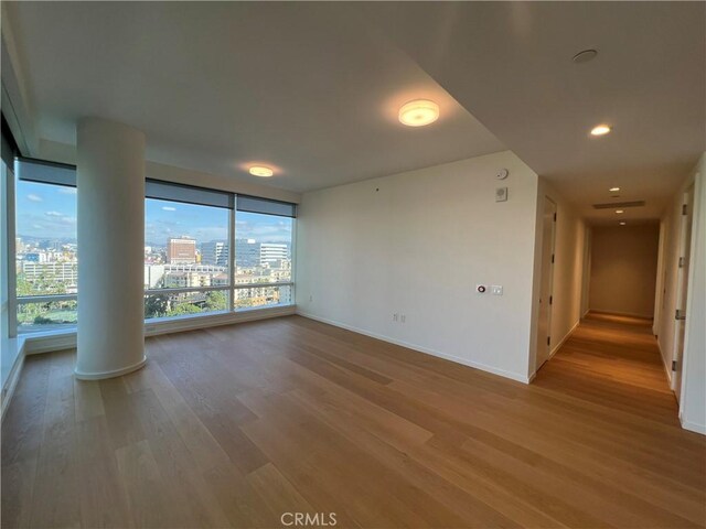 empty room featuring baseboards, a city view, recessed lighting, and wood finished floors