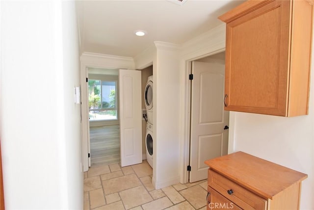 laundry area featuring laundry area, ornamental molding, stacked washer / drying machine, recessed lighting, and stone finish flooring