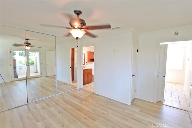 unfurnished bedroom featuring light wood finished floors, crown molding, ceiling fan, and visible vents