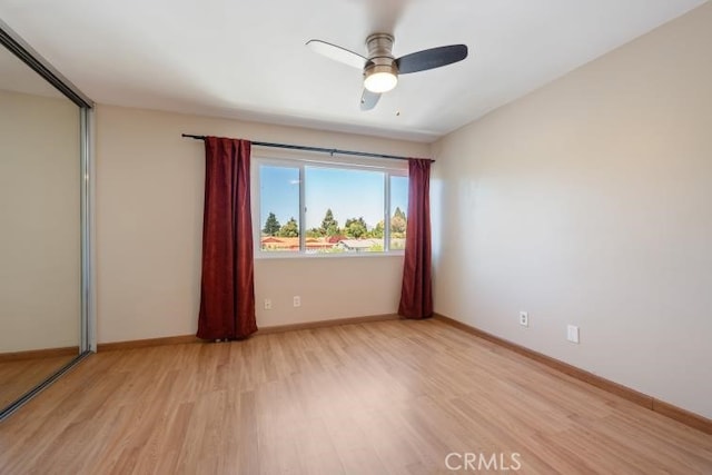unfurnished room with light wood-type flooring, a ceiling fan, and baseboards