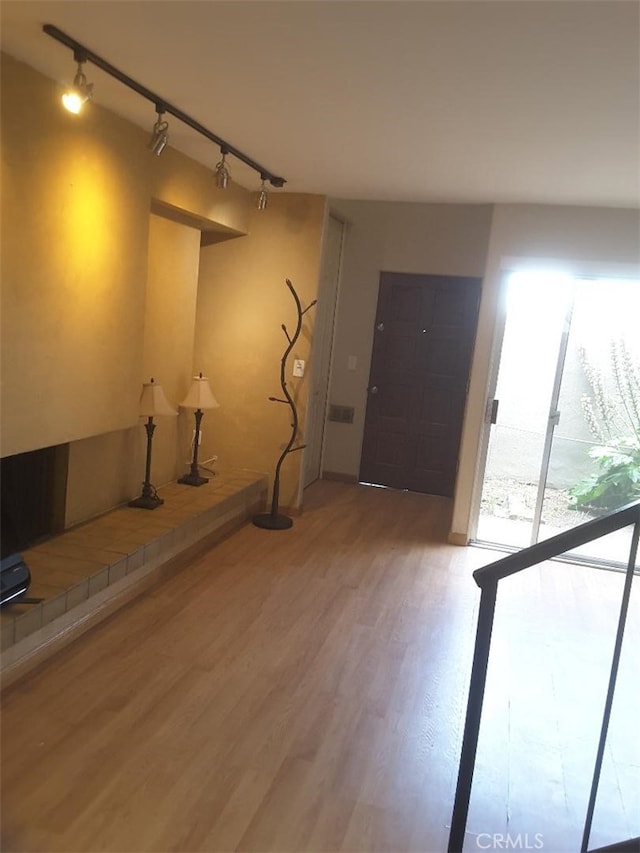 basement with baseboards, track lighting, and light wood-style floors