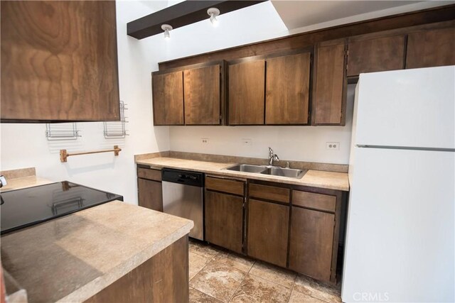 kitchen with a sink, light countertops, freestanding refrigerator, and dishwasher