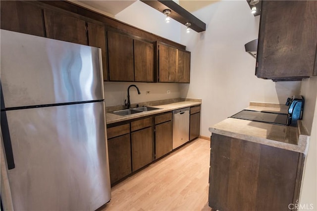 kitchen with appliances with stainless steel finishes, dark brown cabinets, a sink, light countertops, and light wood-style floors