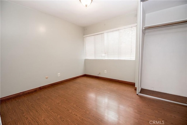 unfurnished bedroom with baseboards, a closet, and wood finished floors