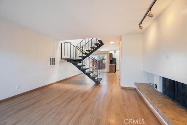 interior space with visible vents, track lighting, stairs, wood finished floors, and baseboards