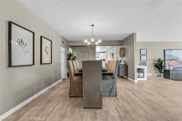 dining space featuring baseboards, visible vents, wood finished floors, and a notable chandelier