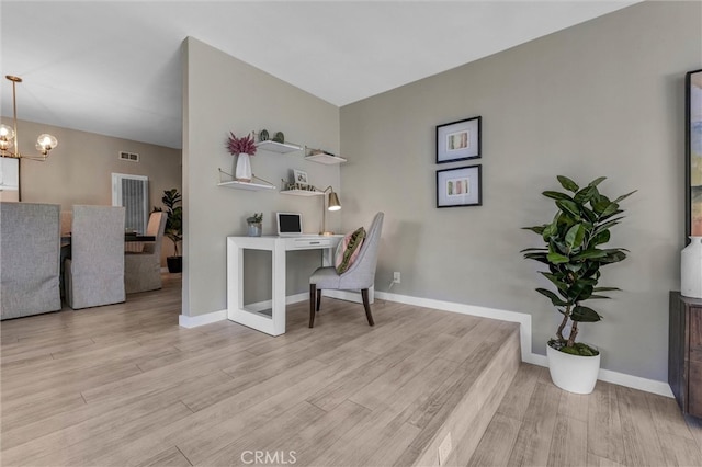 office area with baseboards, visible vents, wood finished floors, and a chandelier