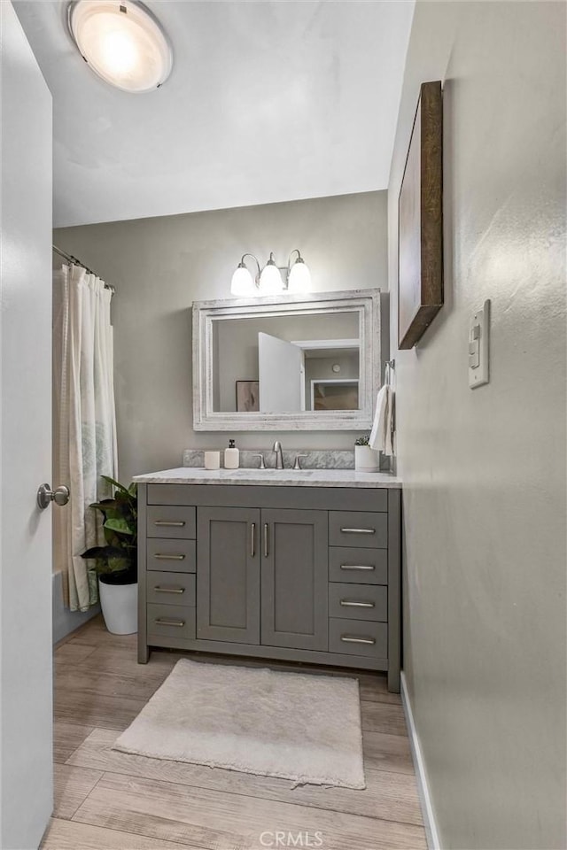 full bathroom featuring baseboards, wood finished floors, and vanity