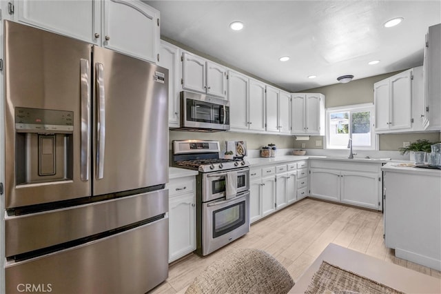 kitchen with recessed lighting, light countertops, white cabinets, a sink, and appliances with stainless steel finishes