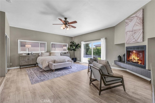 bedroom with access to outside, baseboards, wood finished floors, and a tile fireplace
