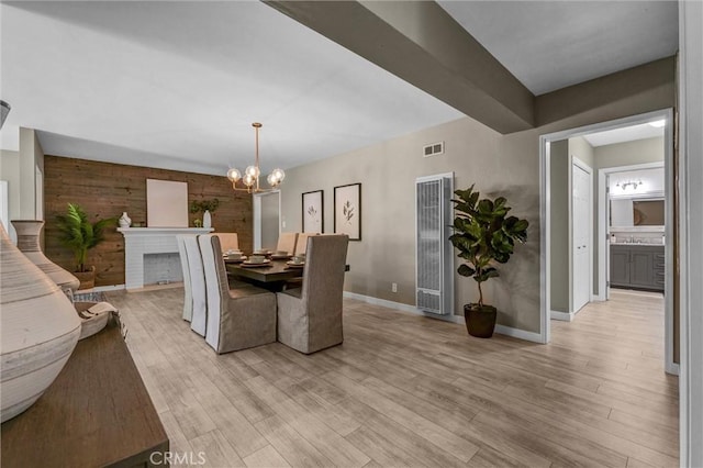 dining space featuring light wood-style floors, baseboards, a chandelier, and a heating unit