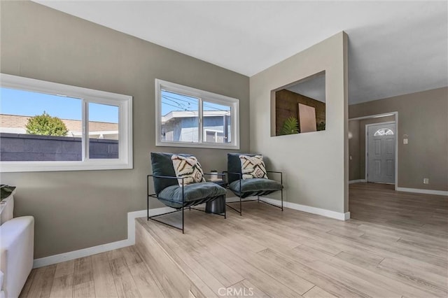 living area featuring baseboards and light wood-style flooring