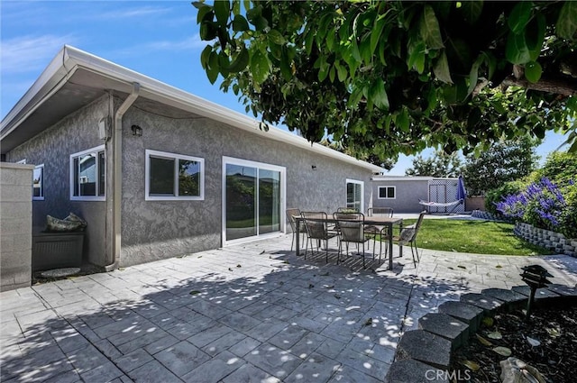 rear view of house featuring a patio, stucco siding, and outdoor dining space