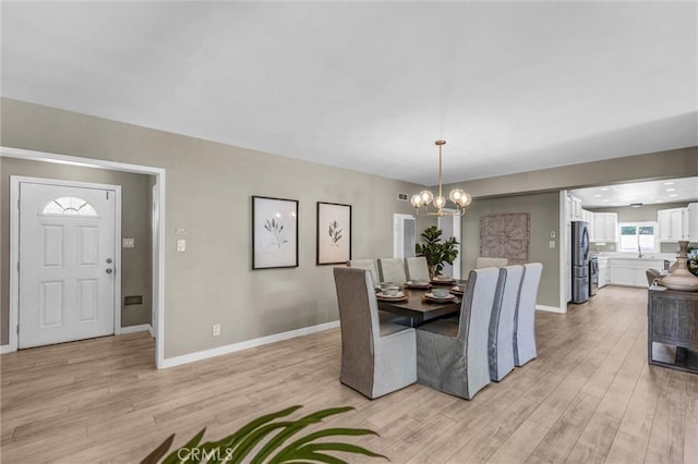 dining room with an inviting chandelier, baseboards, and light wood-type flooring