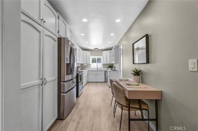 kitchen featuring light countertops, white cabinets, a sink, light wood-style flooring, and stainless steel appliances