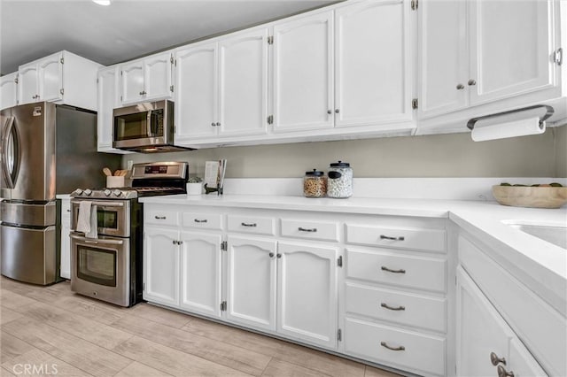 kitchen featuring light countertops, appliances with stainless steel finishes, white cabinets, and light wood-type flooring