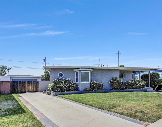 view of front of house featuring stucco siding, fence, a front yard, and concrete driveway