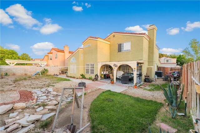 rear view of property featuring a fenced backyard, stucco siding, and a patio area