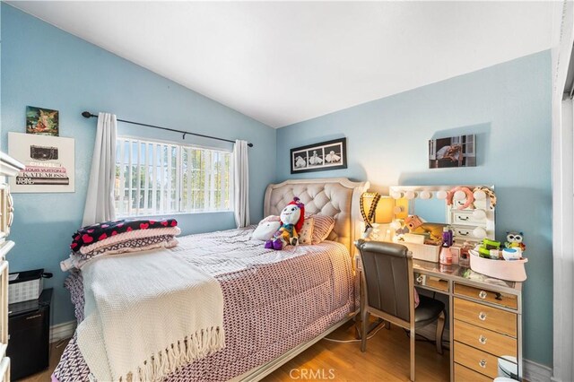 bedroom with vaulted ceiling and wood finished floors