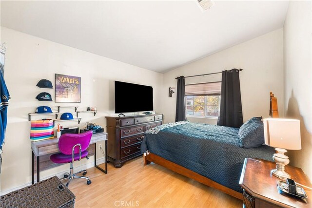 bedroom with vaulted ceiling, wood finished floors, and visible vents