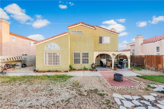 rear view of house with a fenced backyard, stucco siding, a fire pit, and a patio area