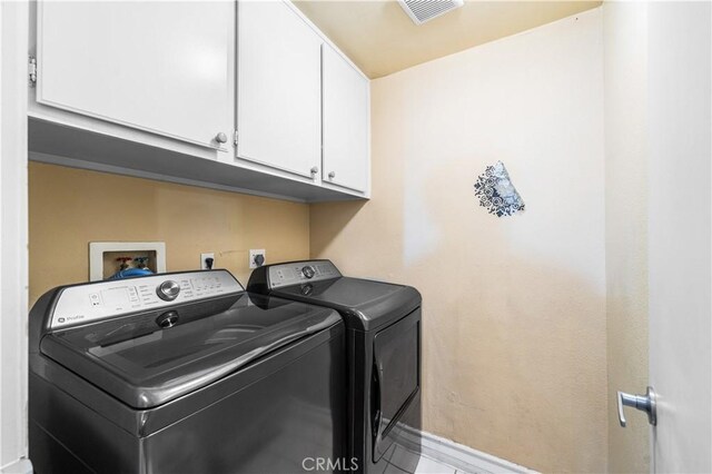 laundry area with baseboards, washing machine and dryer, cabinet space, and visible vents