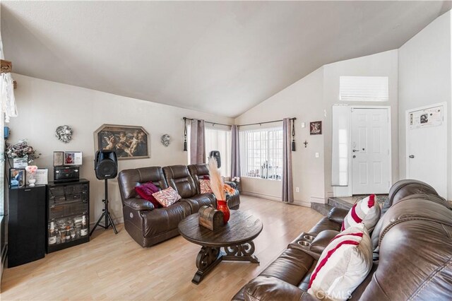 living area featuring light wood finished floors and high vaulted ceiling