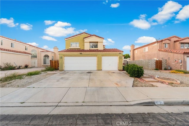mediterranean / spanish-style house with a tiled roof, driveway, fence, an attached garage, and stucco siding