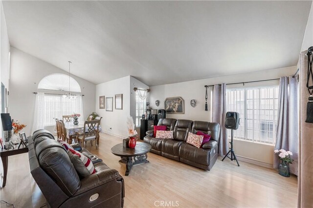 living area featuring light wood-style floors, a chandelier, and lofted ceiling