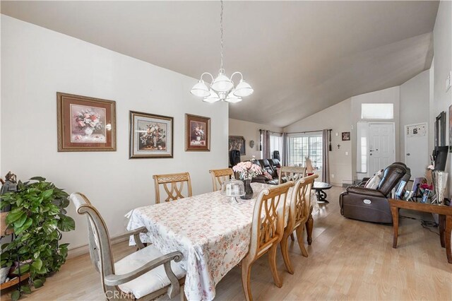 dining area featuring baseboards, a notable chandelier, light wood-style flooring, and lofted ceiling