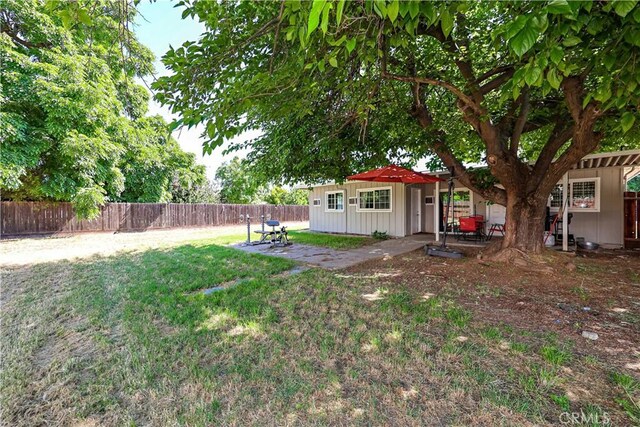 view of yard with an outdoor structure, a fenced backyard, and a patio area