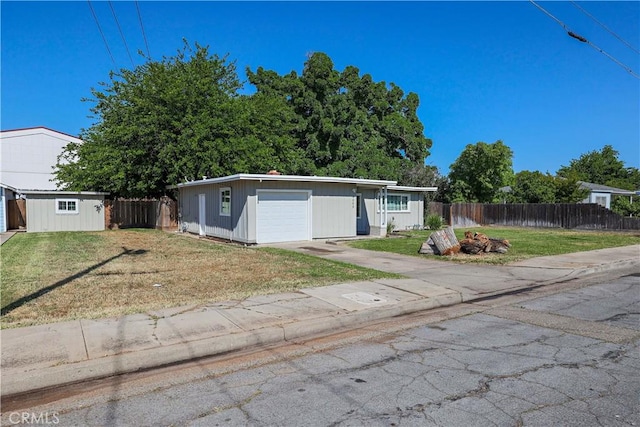 ranch-style house with concrete driveway, fence, a shed, and a front yard