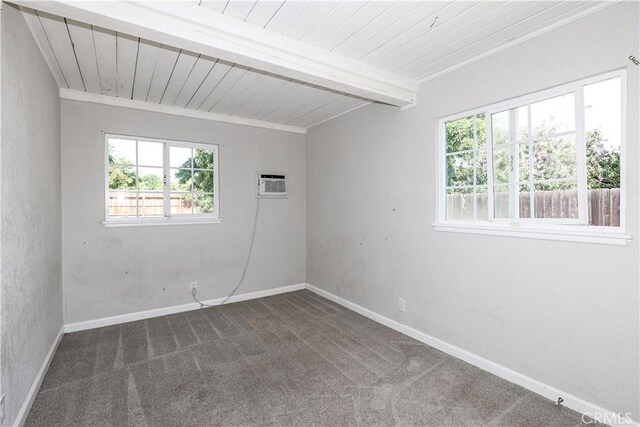 carpeted spare room with wooden ceiling, baseboards, a wall mounted AC, and beam ceiling