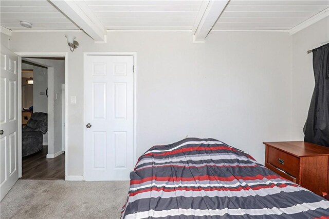 carpeted bedroom with baseboards, ornamental molding, and beamed ceiling