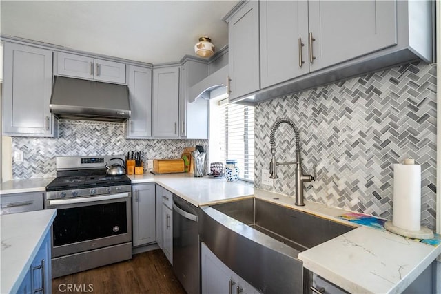 kitchen with stainless steel appliances, under cabinet range hood, gray cabinetry, and a sink
