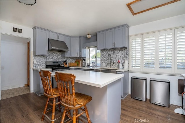 9810 Sharon Ave, Riverside, CA 92503 - kitchen with gray cabinetry, stainless steel electric range, under cabinet range hood, light countertops, and backsplash