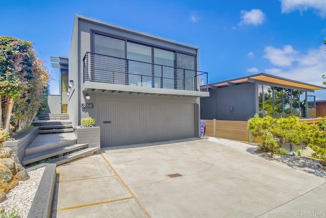modern home with stairway, an attached garage, driveway, and a balcony