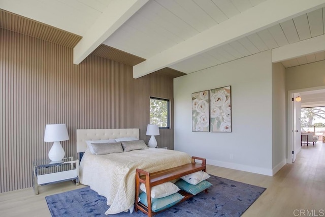 bedroom with baseboards, wood walls, beam ceiling, and wood finished floors